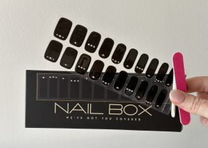 A female holding black with pearl and gold dots Semi Cured Gel Nail Sticker Kit sold by Nail Box